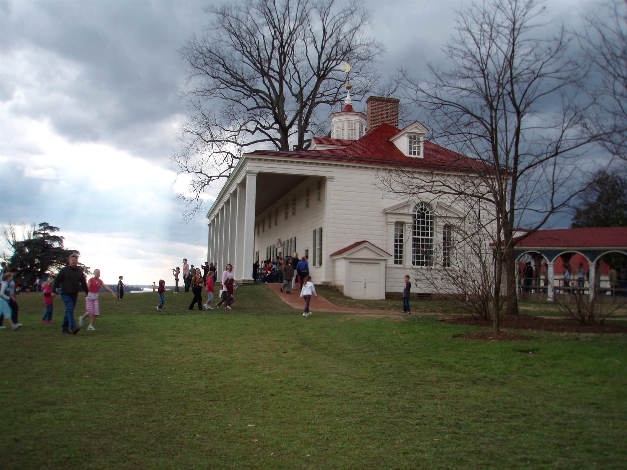 Families walk across the lawn in front of Mount Vernon, George Washington's historic home.