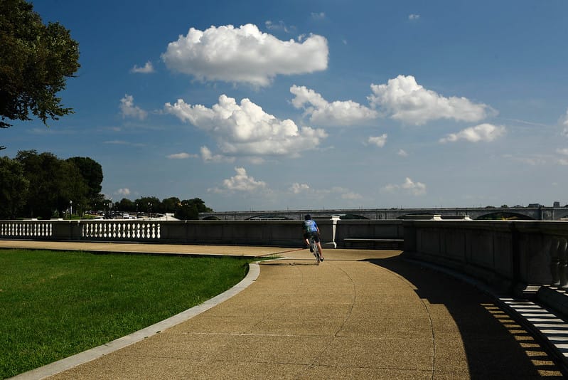 A cyclist rides on a sidewalk along the Potomac River, near the National Mall.