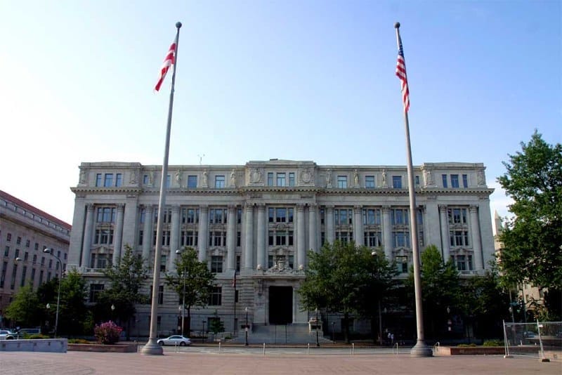 A large grey building stands behind two flag poles in downtown D.C. 