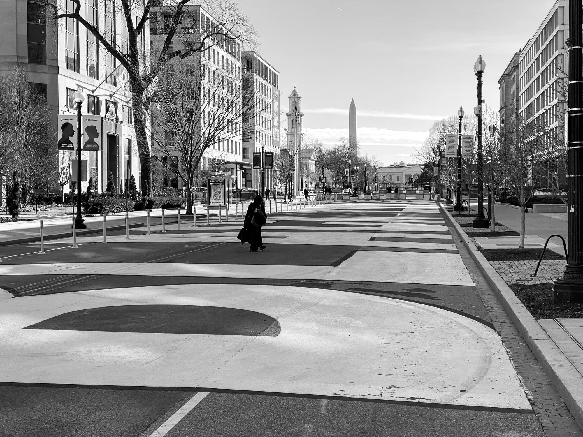 A person walks through Black Lives Matter Plaza in Washington D.C. with the Washington Monument and other buildings in the background.