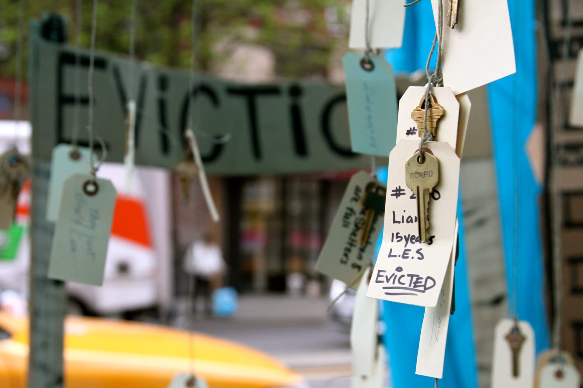 A photograph of keys hanging, one has a tag that has someone's name and "15 years," "evicted."