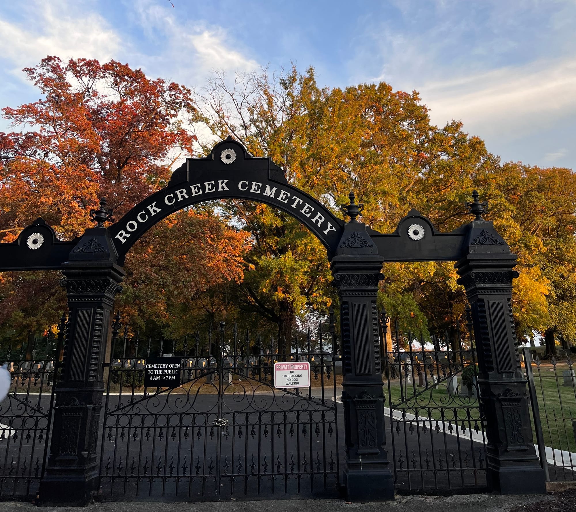 The gates to Rock Creek Cemetery with fall foliage visible in the background.