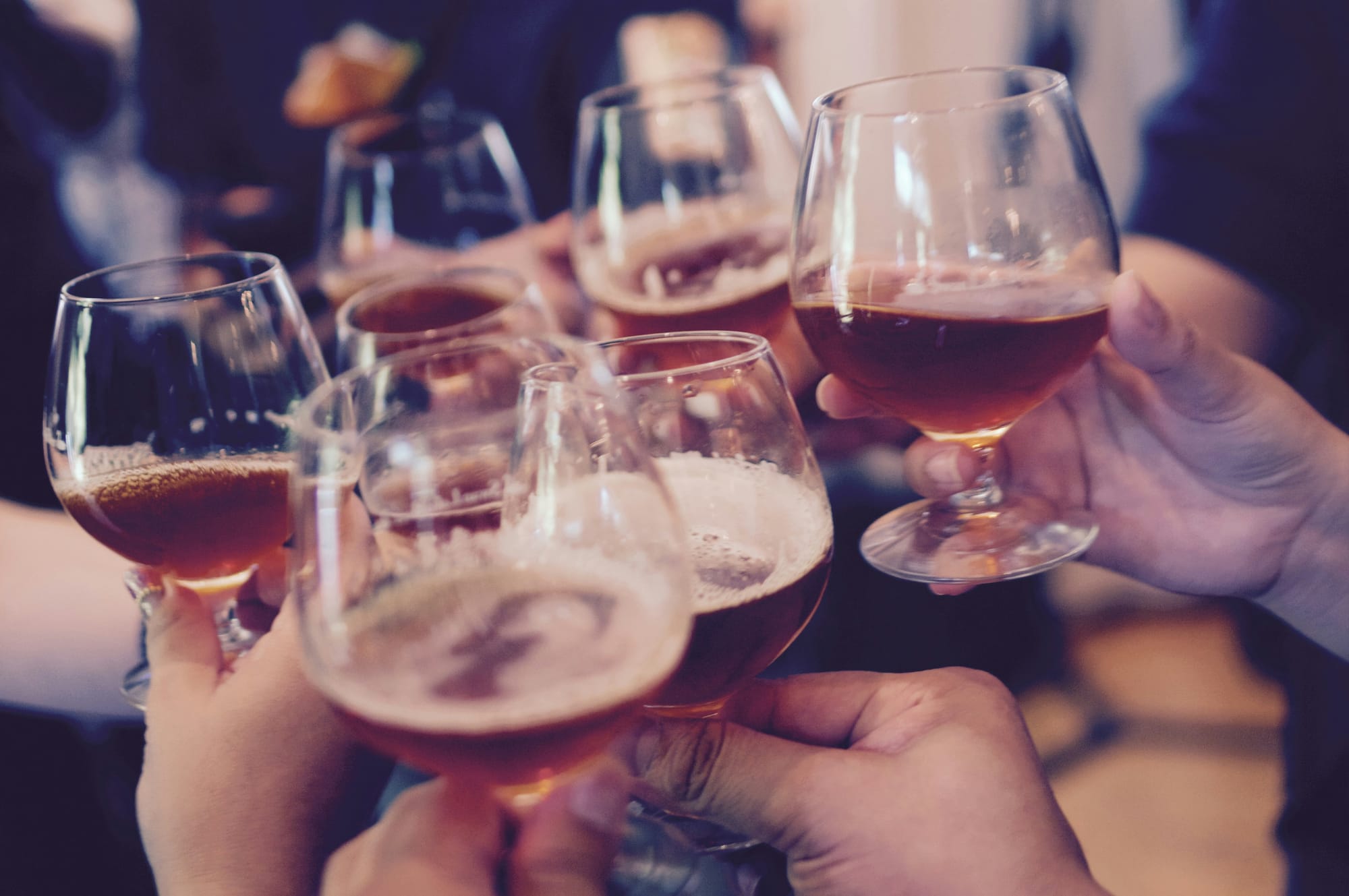 A group of people's hands shown cheersing goblets of beer.