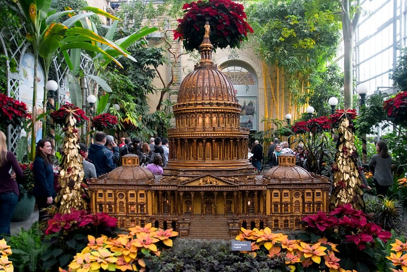 Bronze capital display surrounded by flowers inside the Botanical Gardens.