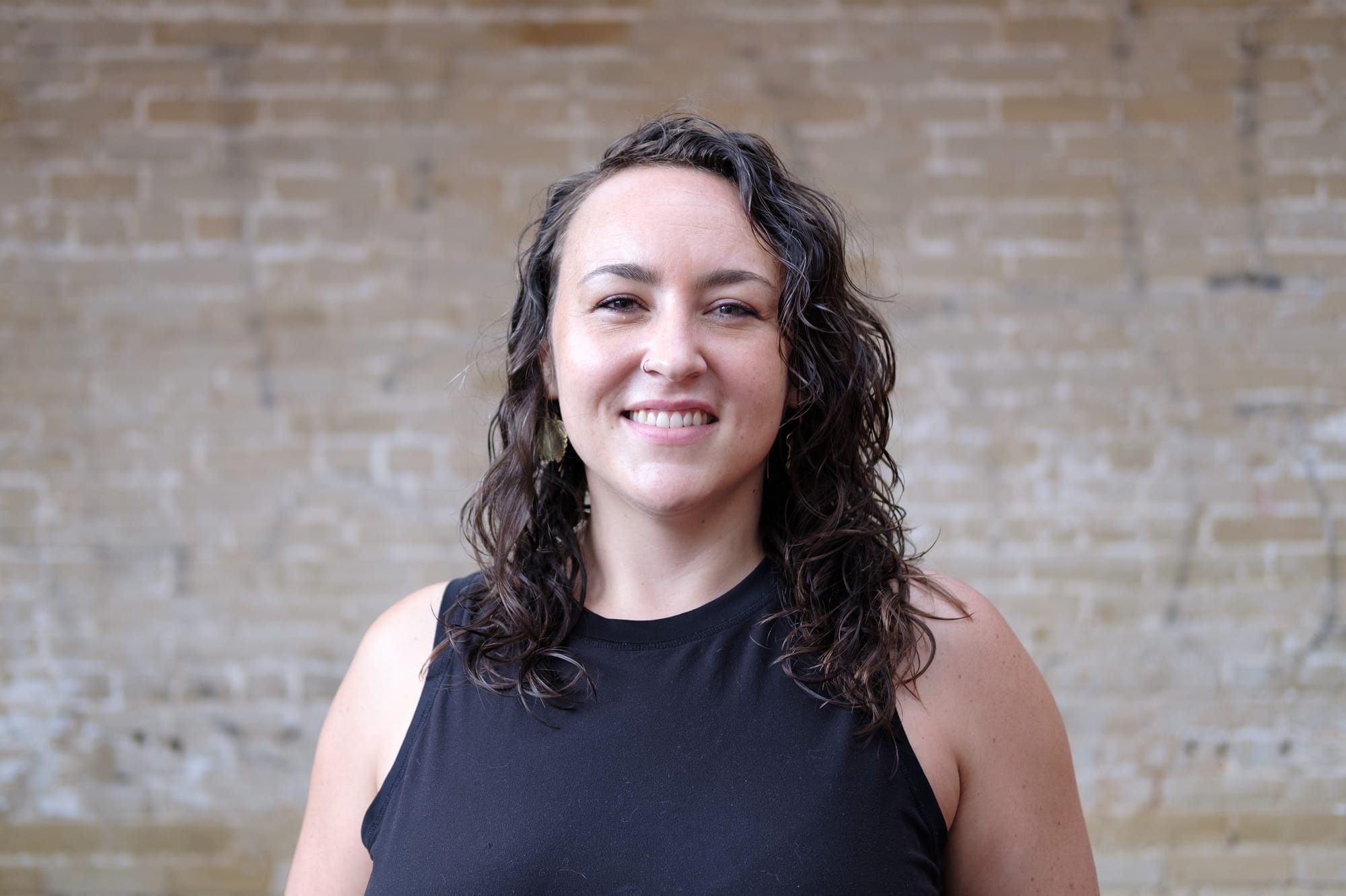 A photo of Abigail Higgins standing outside in front of a brick wall.