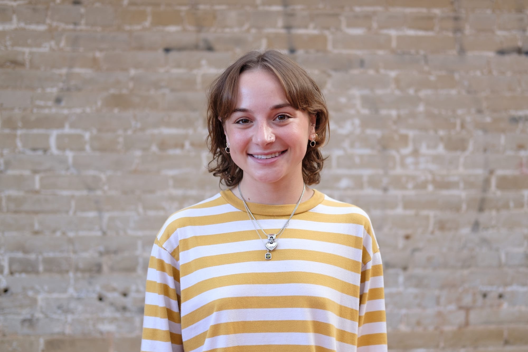 A photo of Colleen Grablick outside, standing in front of a brick wall.