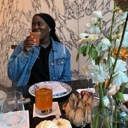 Photo of Cornelia at a dining table set with flowers and pumpkins, lifting a glass.