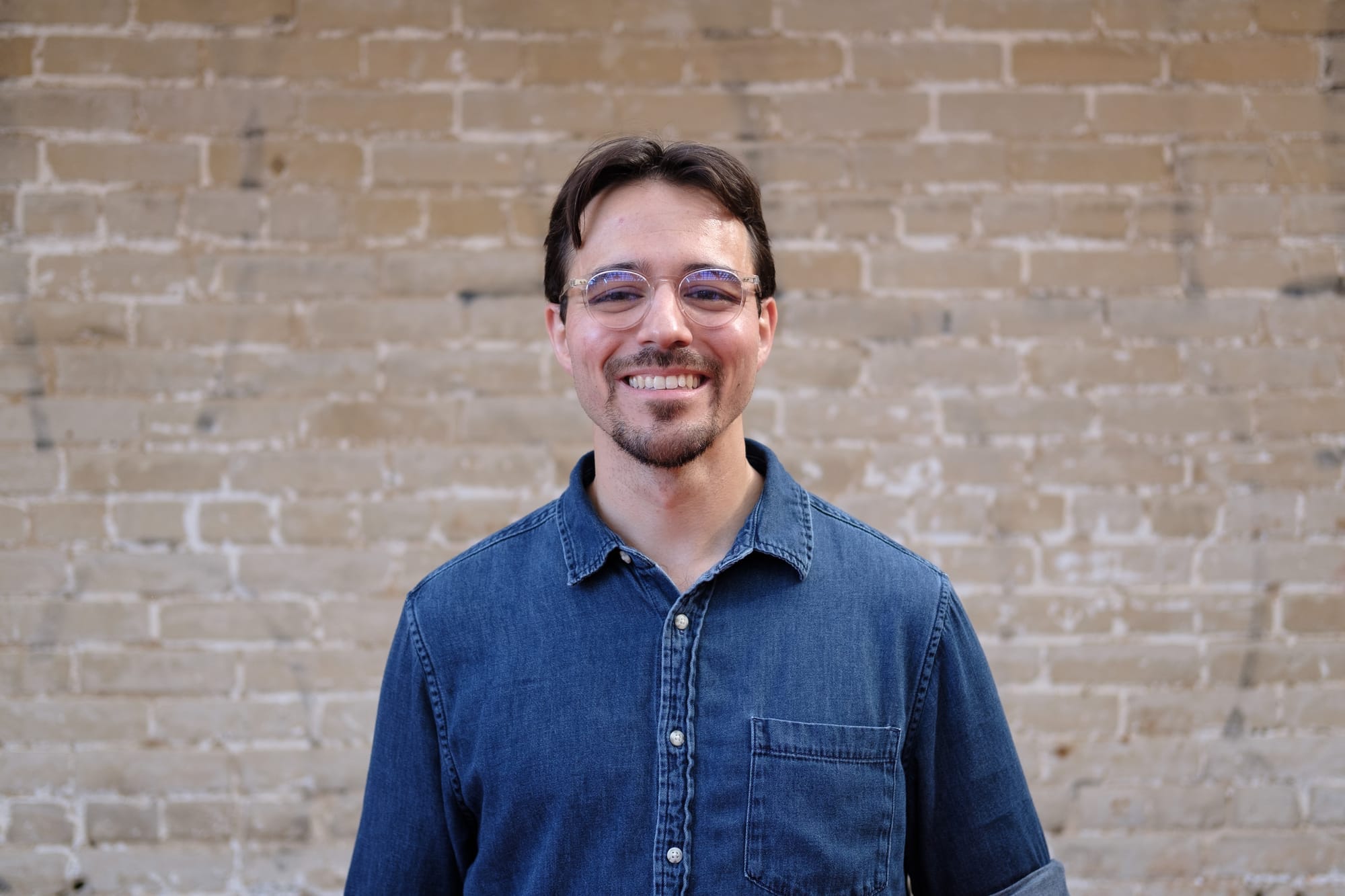 A photo of Eric standing outside in front of a brick wall.