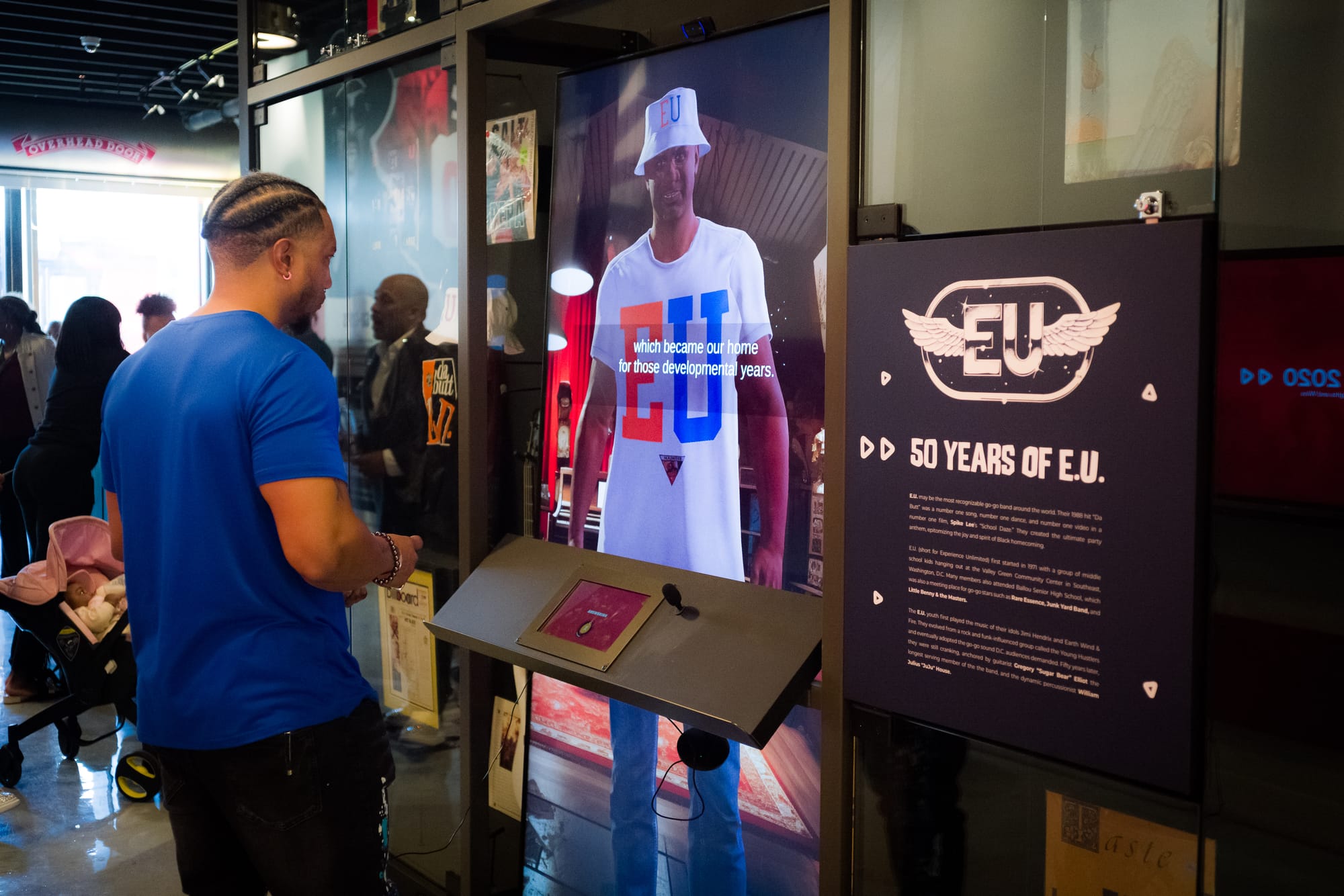 A Black man stands in front of a hologram of Sugar Bear. 