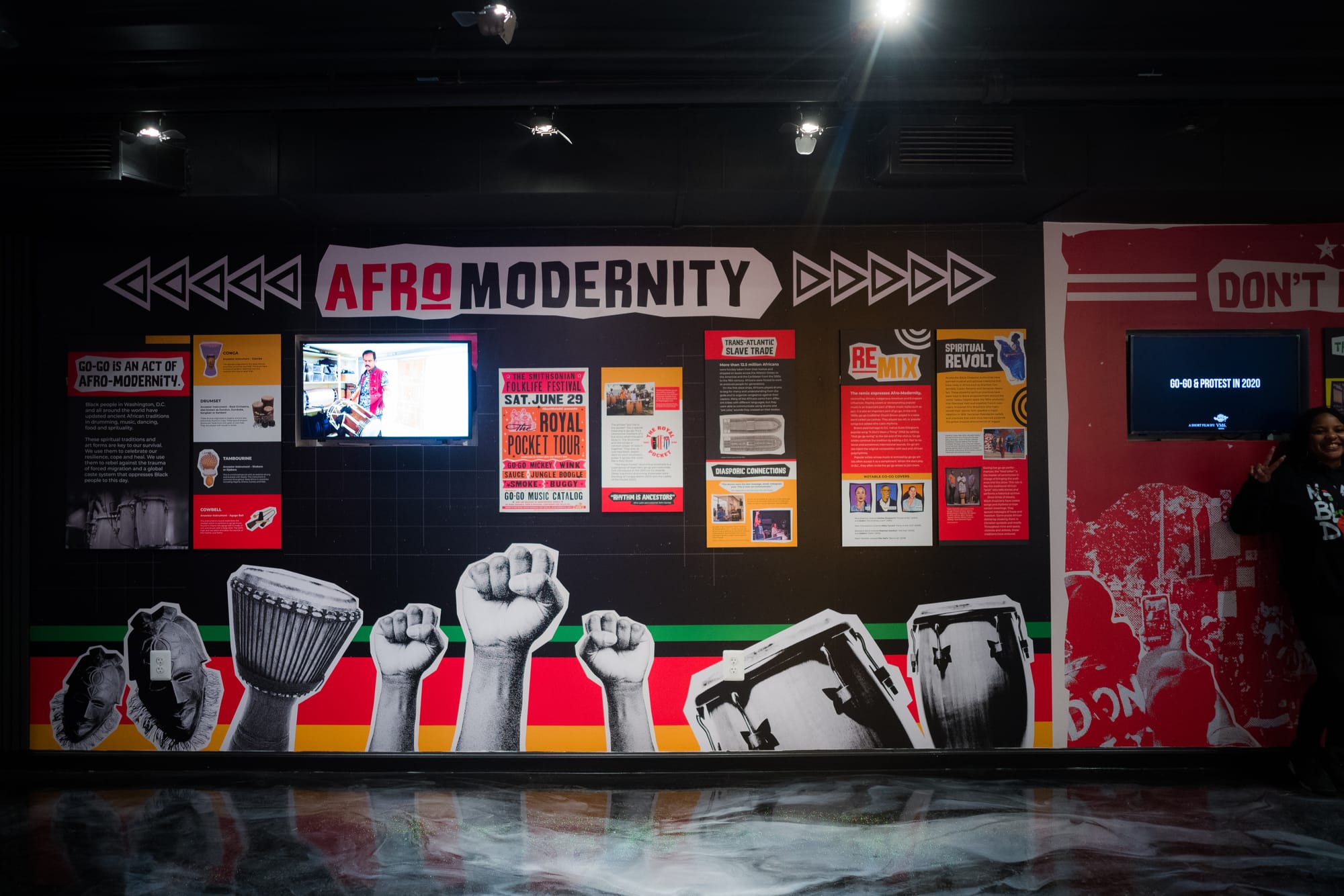 A wall is lined with infographics and art of raised fists and drums. The wall reads "AFROMODERNITY"