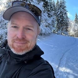 Photo of Martin outside on a snow-covered road with trees behind him.