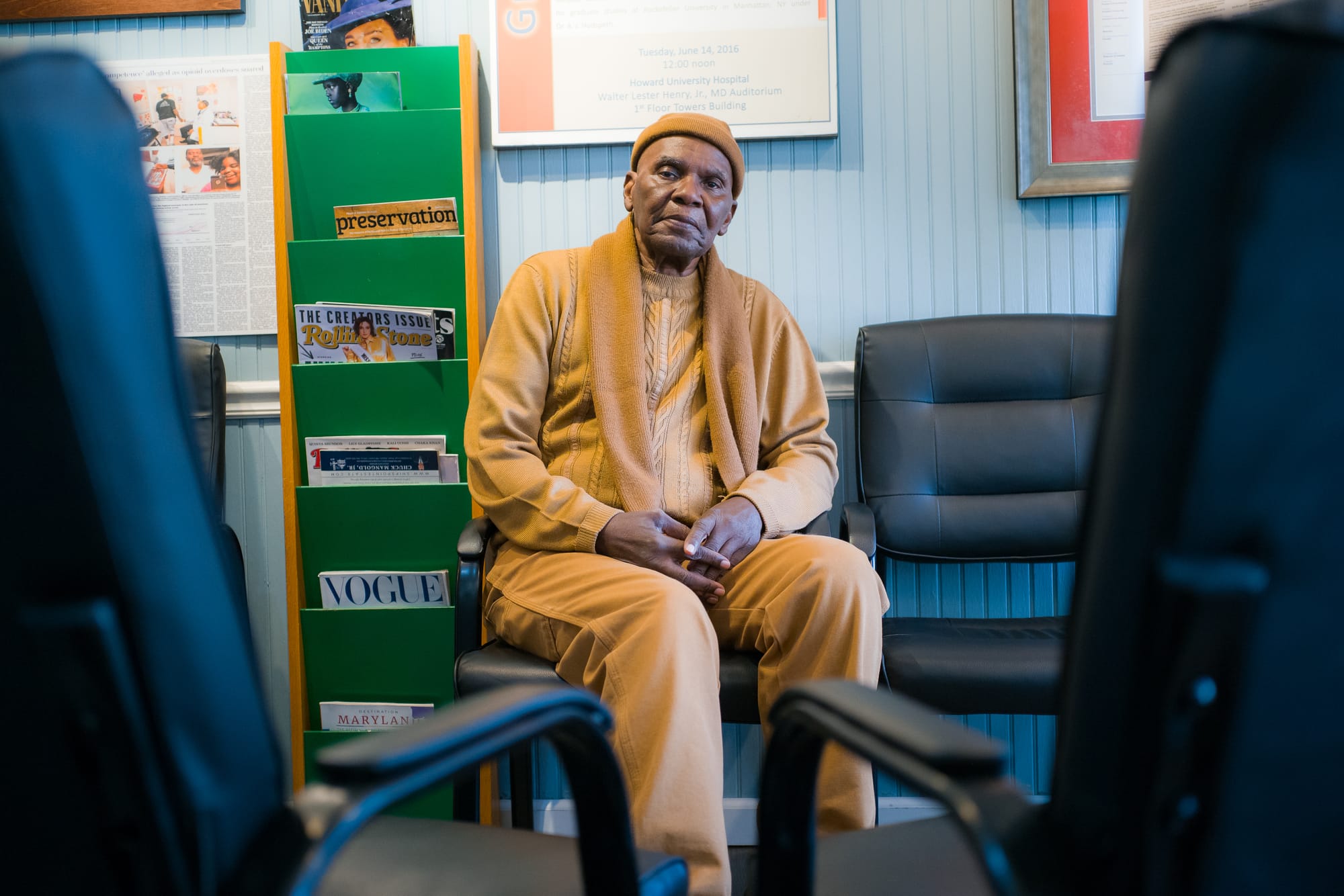 A picture of an older man in a doctor's office in a mustard yellow outfit.