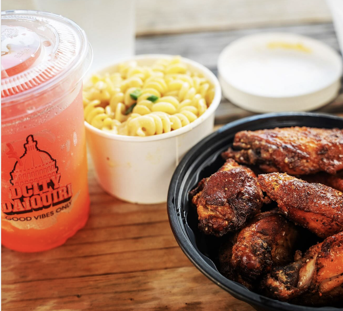 A restaurant meal including a red drink, cheesy pasta, and grilled chicken wings.