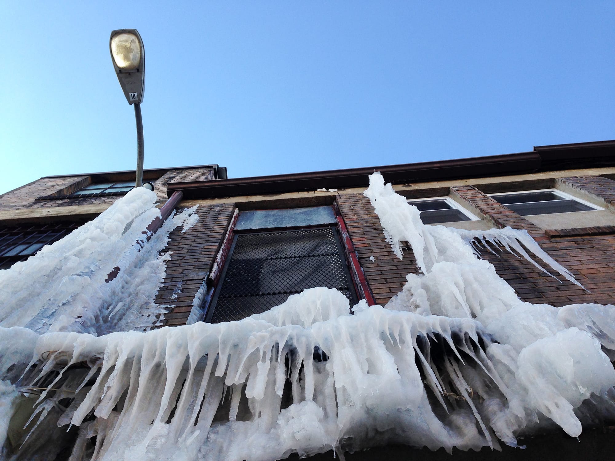 Iciles hanging off a brown and red brick building. 