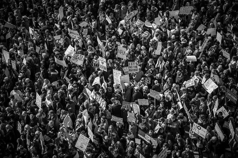 A black and white aerial photo of a large march with people holding protest signs.