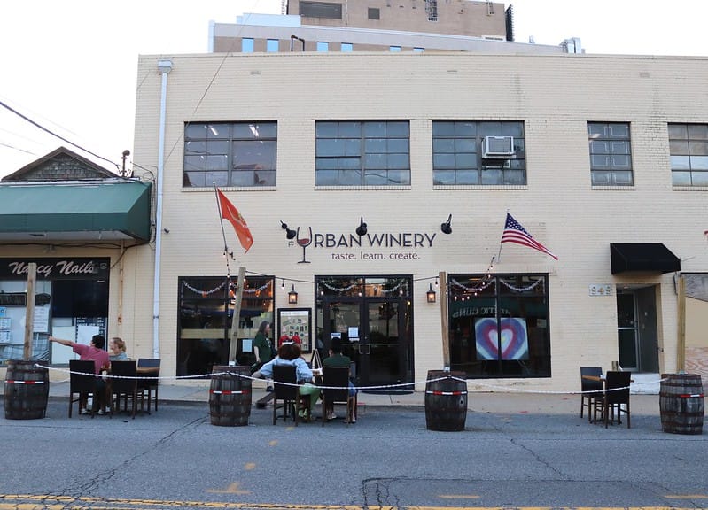 Outside of a tan building with the name Urban Winery.