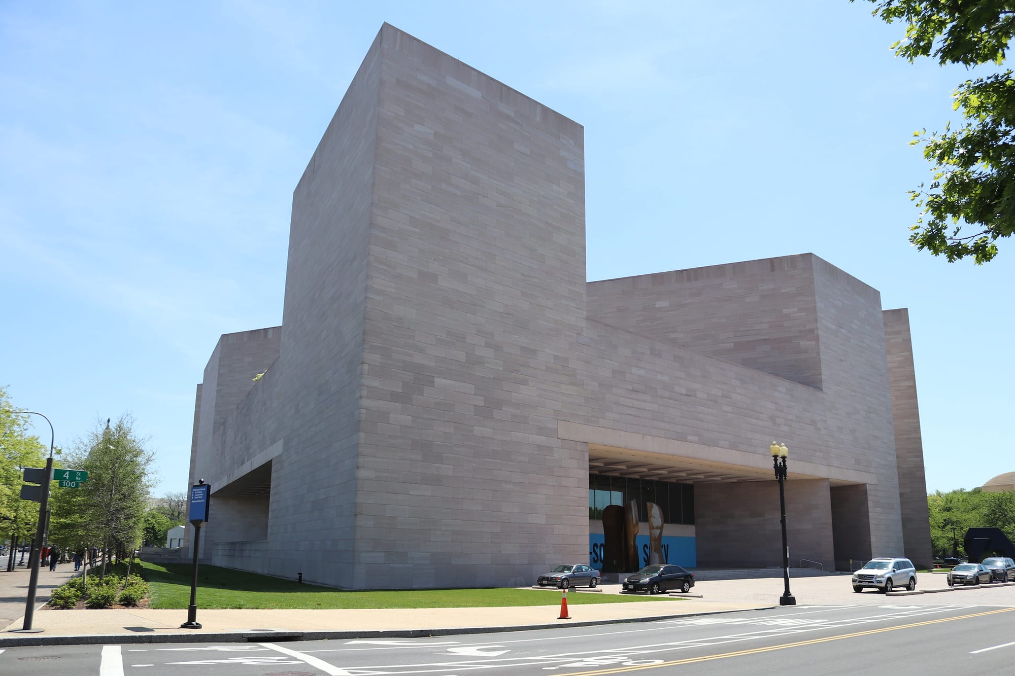 A cubic building sits on a corner on a sunny day. 