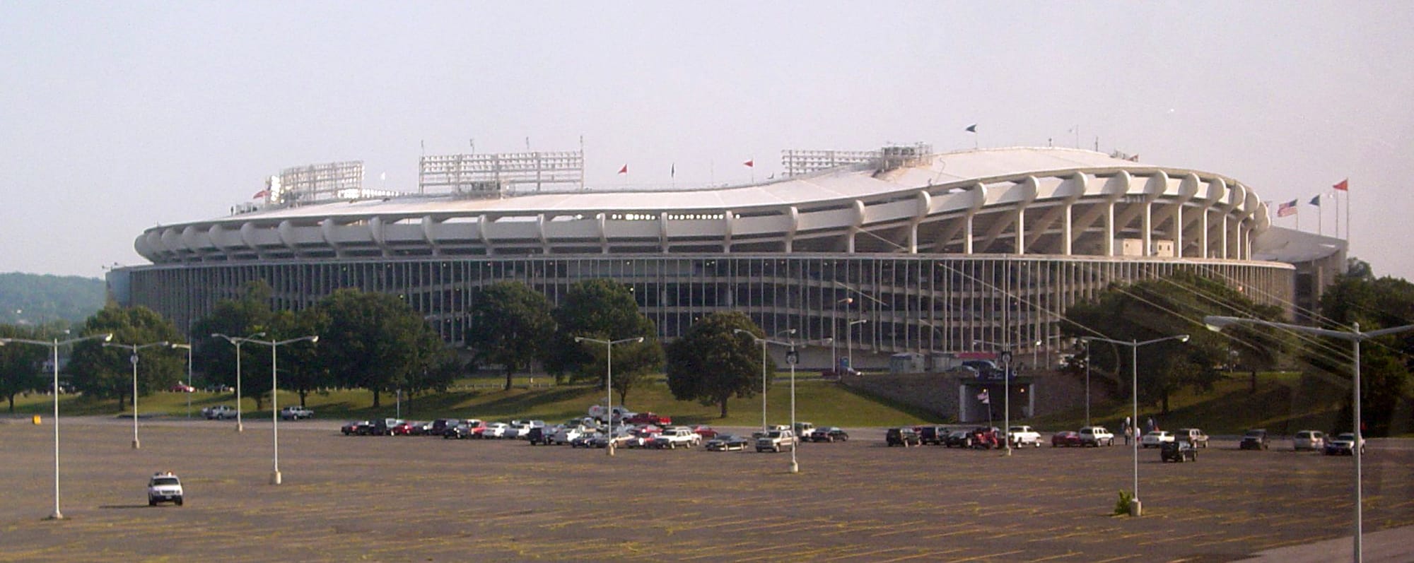 Outside shot of a large stadium with a few cars in a parking lot.