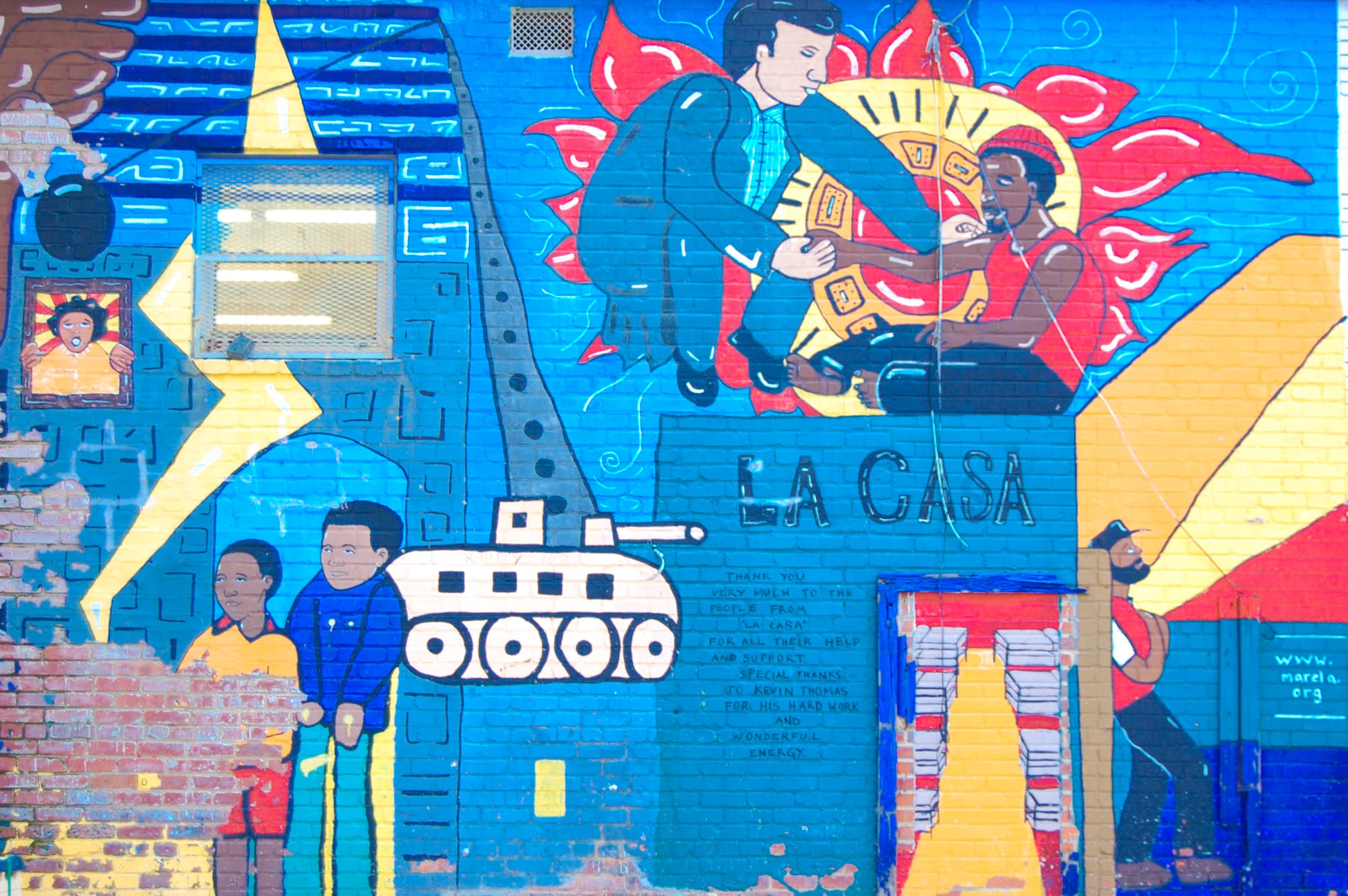 A photograph of a colorful mural on a brick wall with people and the words "La casa."