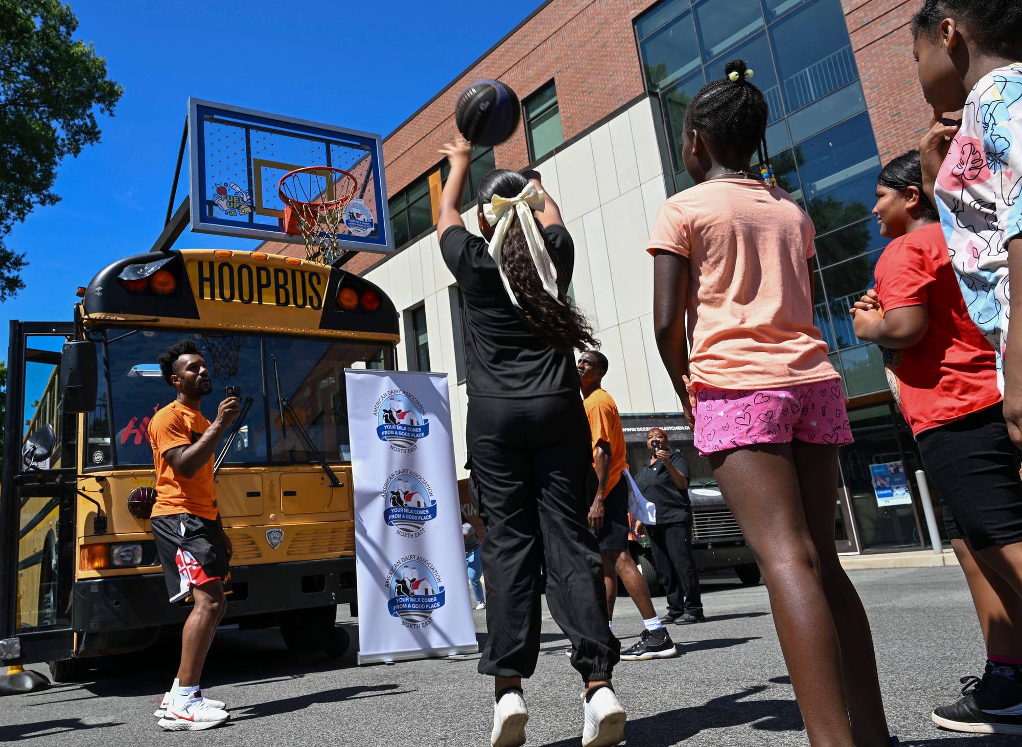 A group of kids play basketball outside. 