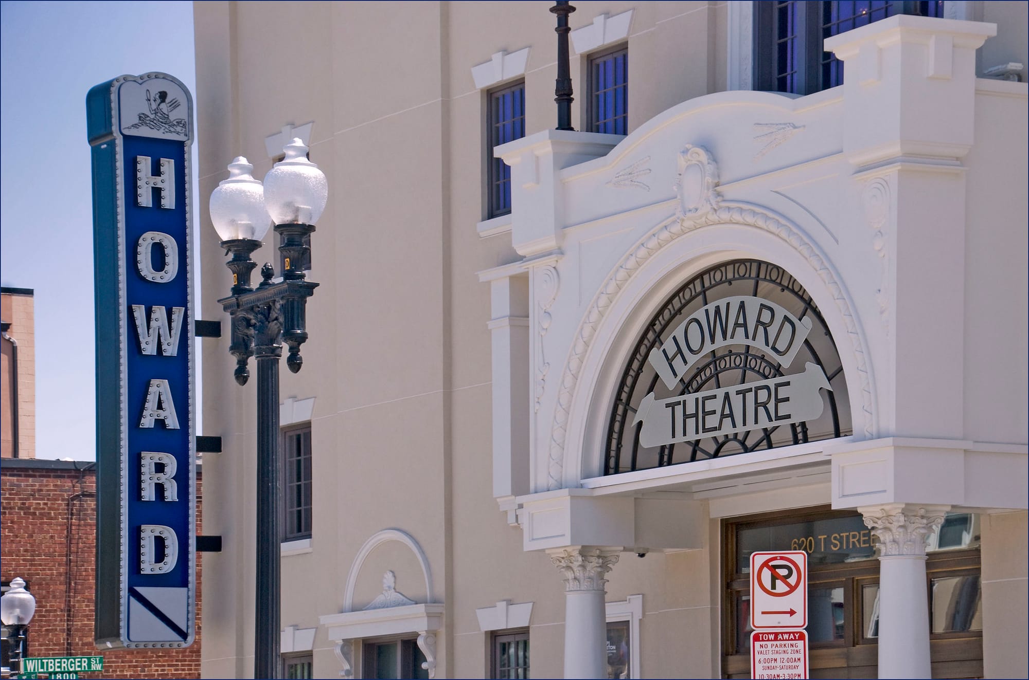 A white building reading Howard Theatre in an arch, with a unlit vertical sign that read HOWARD.