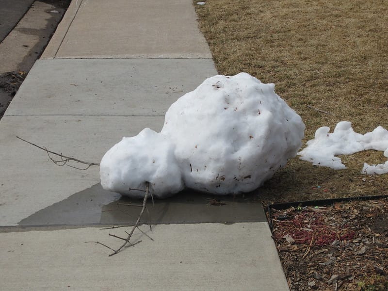 Overturned snowman on sidewalk.