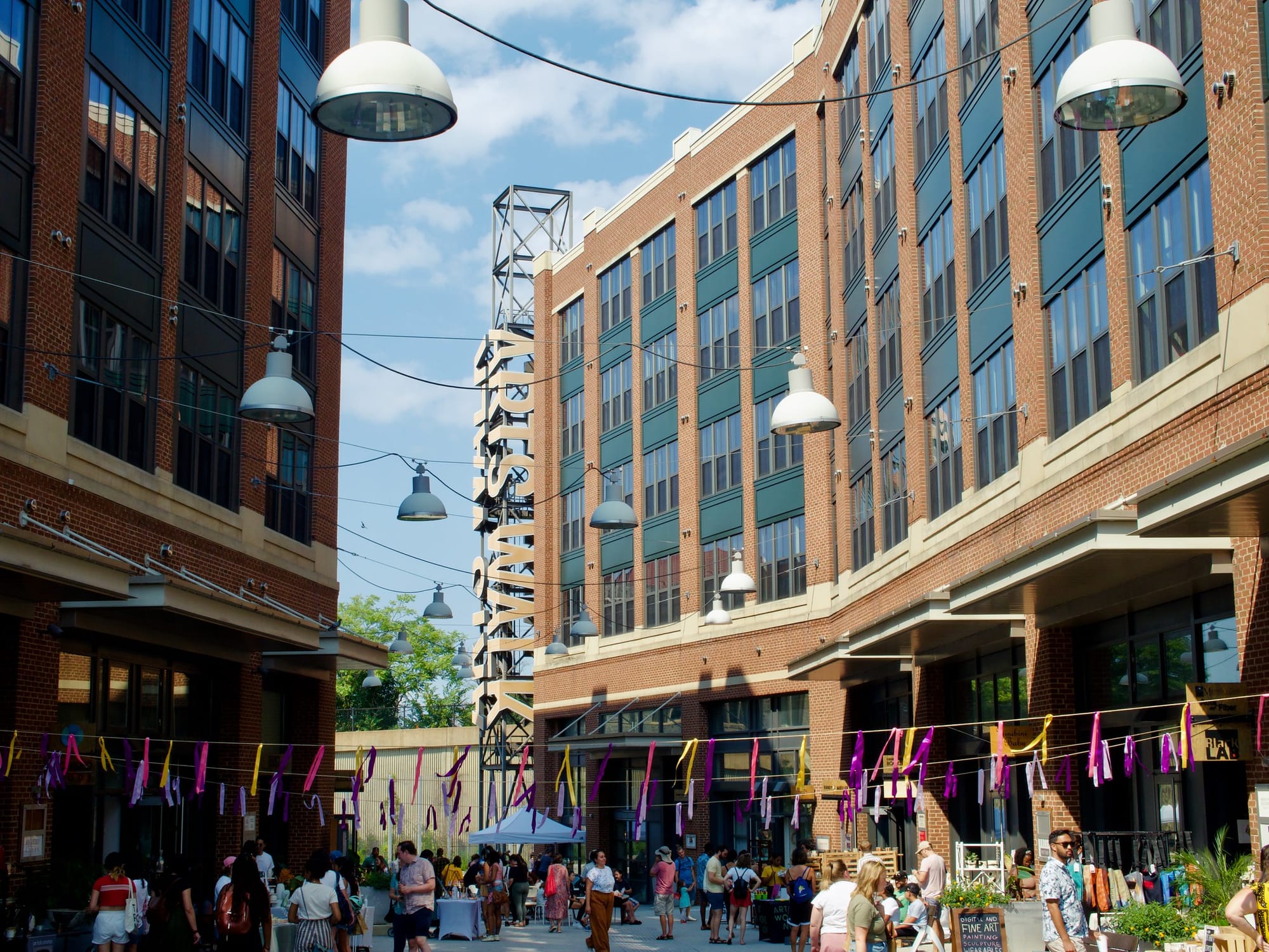 An alleyway populated with shoppers, hugged by two buildings. 