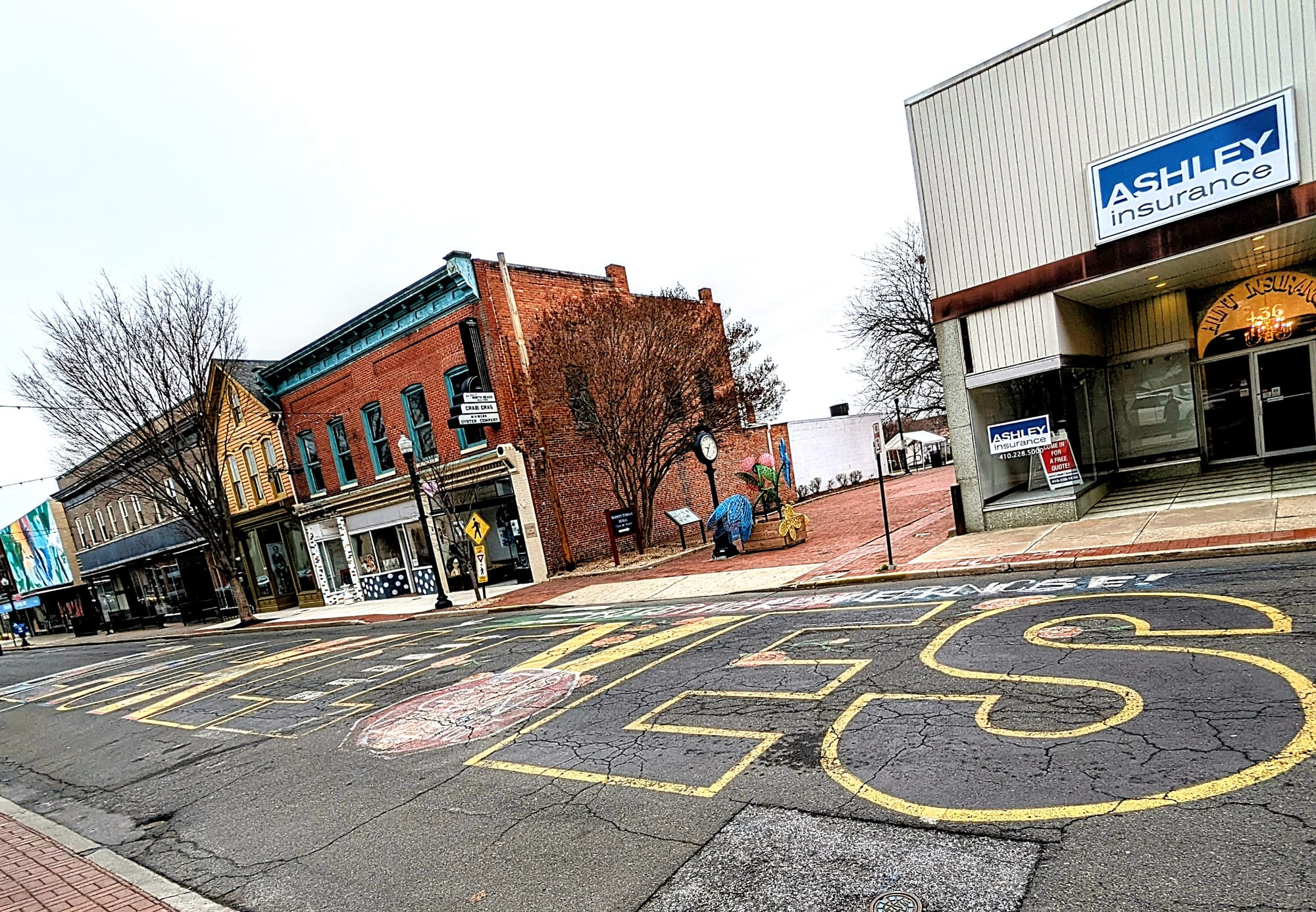 A photo showing five buildings lining a road where the outline text of "BLACK LIVES" is visible with various designs, including part of the Maryland flag pattern, filling the outlines.