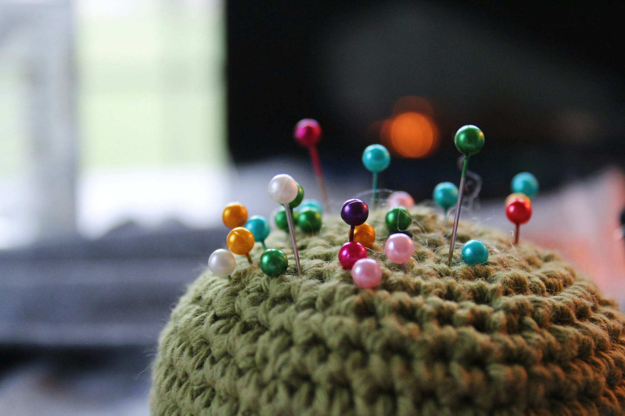 A knit ball stuck with multi-colored pins. 