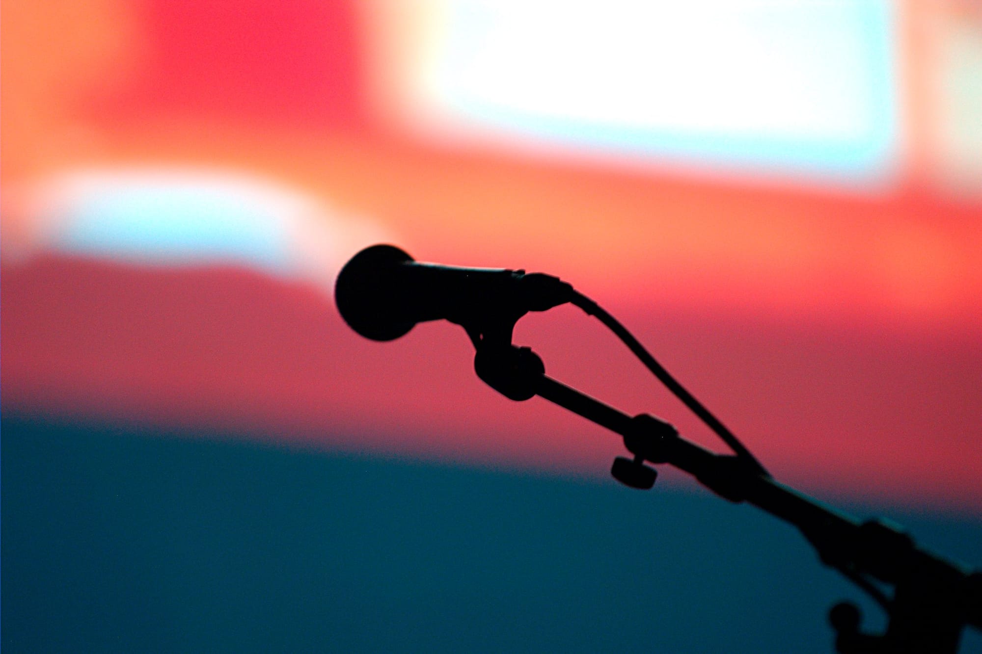 A microphone hooked into a stand with a screen in the background