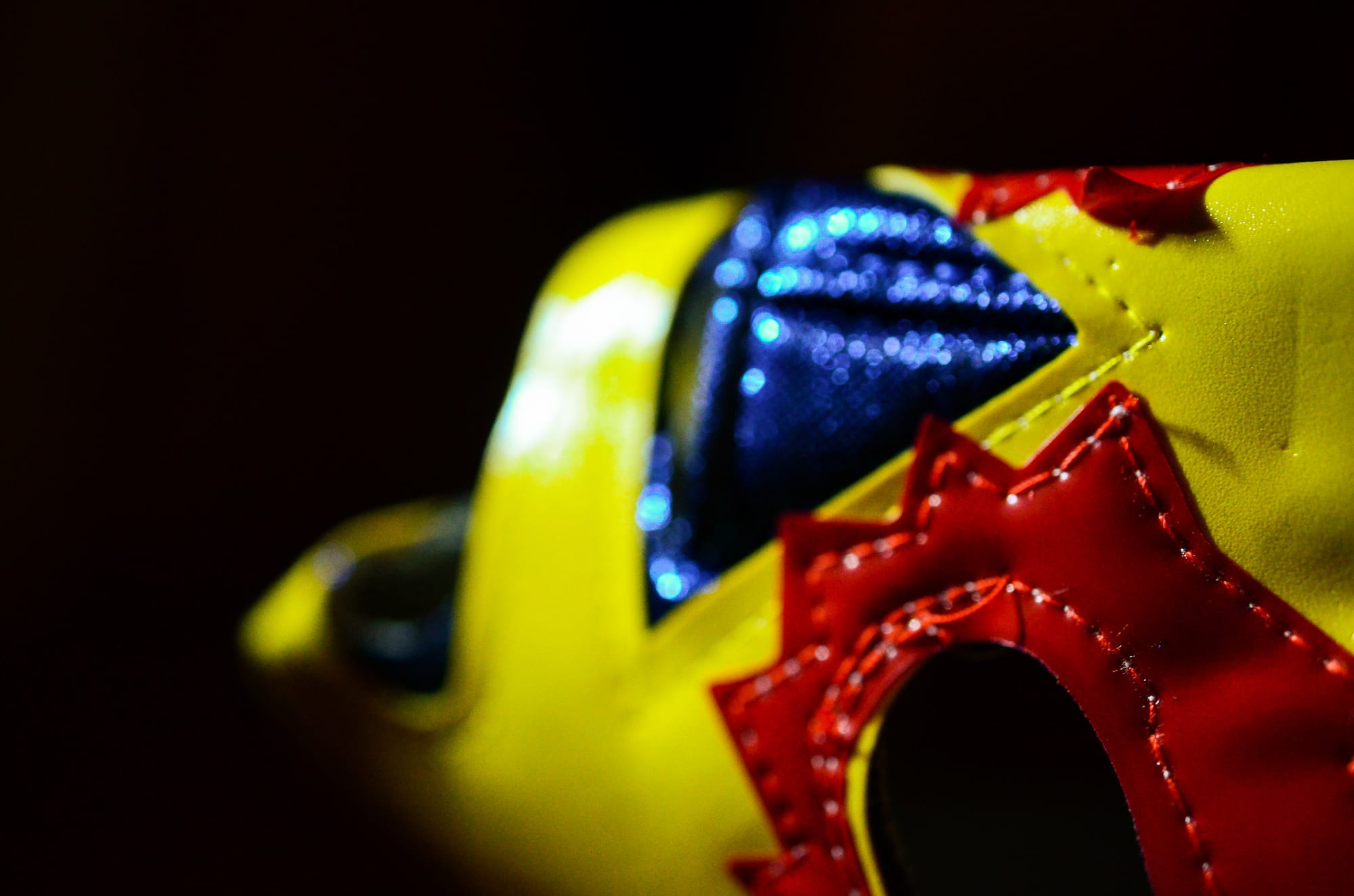 A yellow luchador mask with red and blue detail