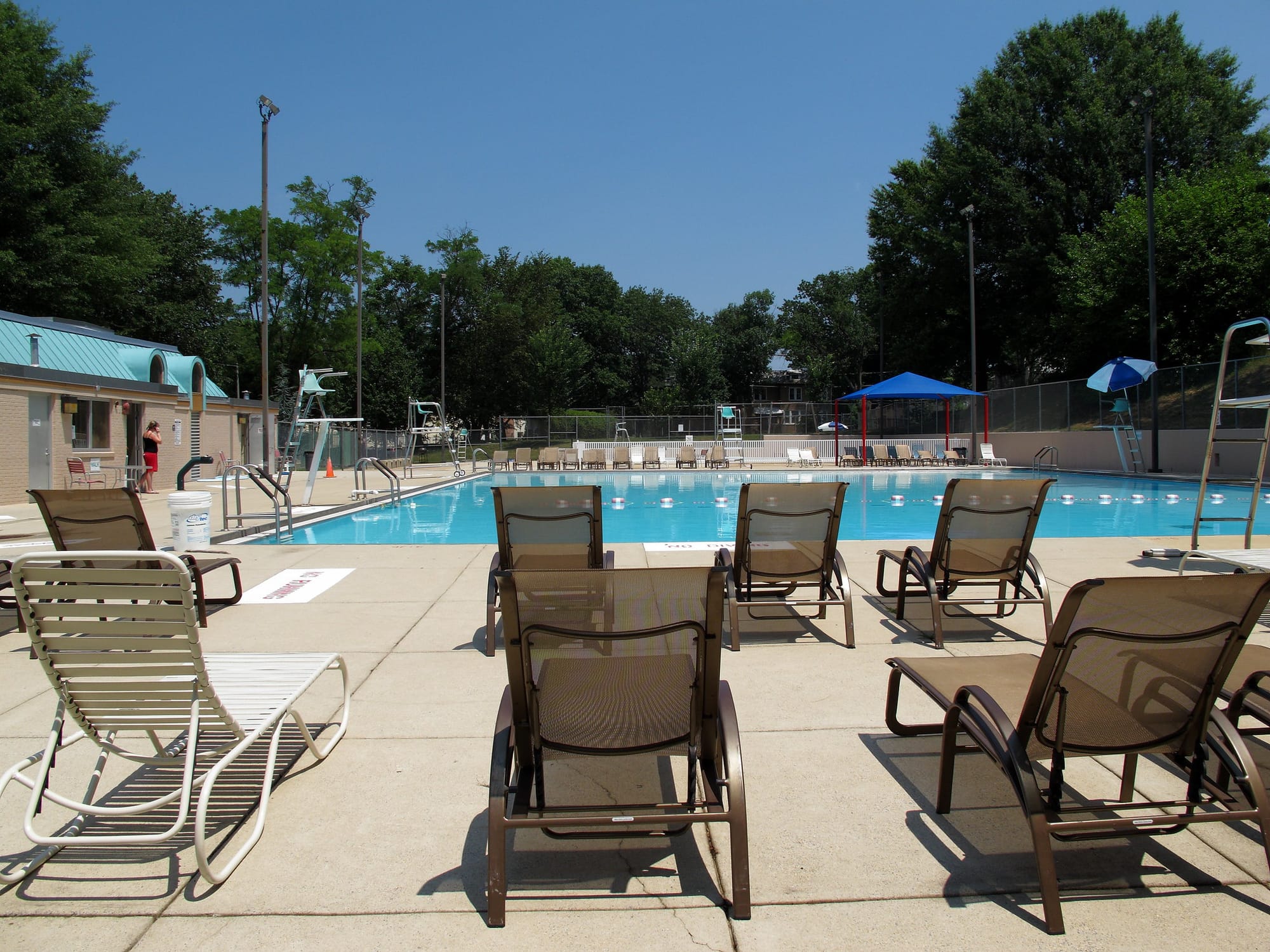 A photo of empty pool chairs in front of a swimming pool
