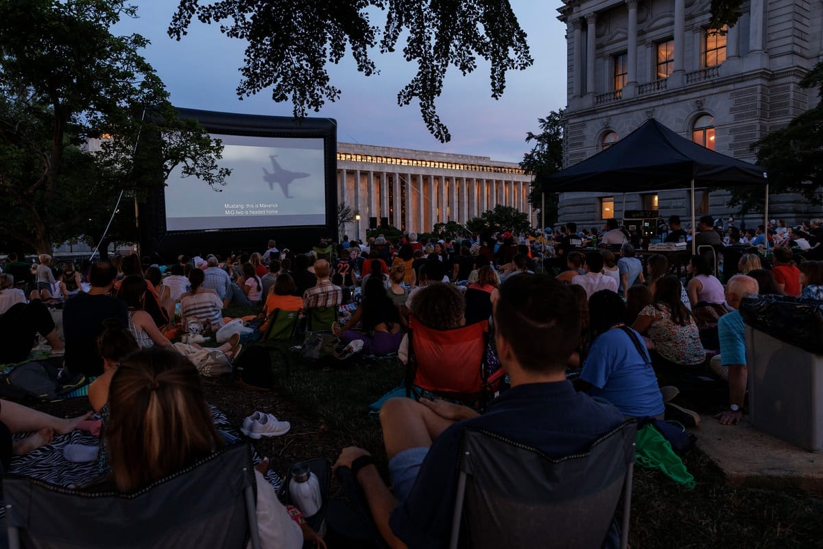 A gathering at dusk before a screen. 