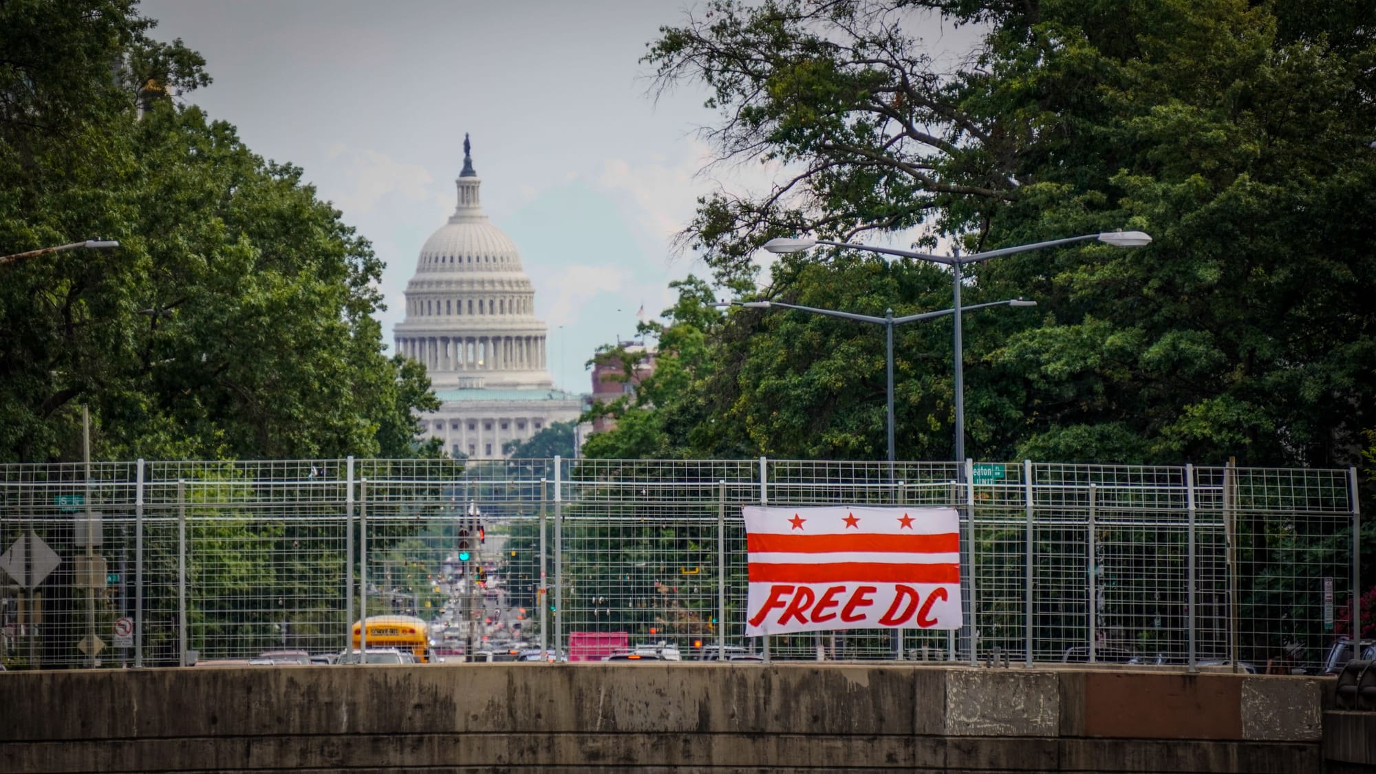 A flag hanging over a bridge that reads FREE DC with the Capitol in the background. 