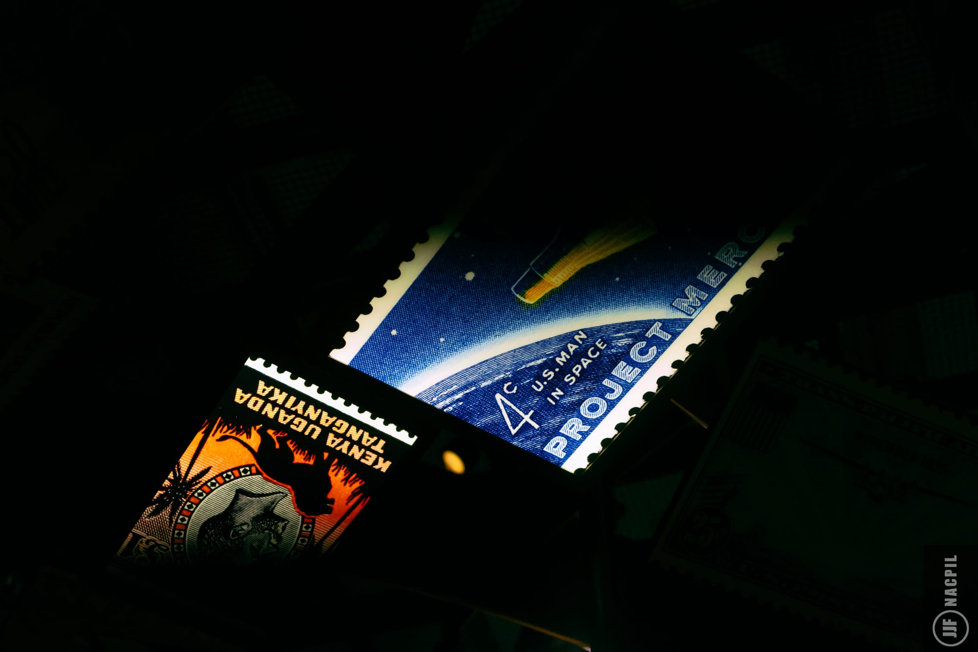 Two postage stamps, one reading "Kenya, Uganda, Tanganyika" and the other reading "U.S. man in space" with a black background.