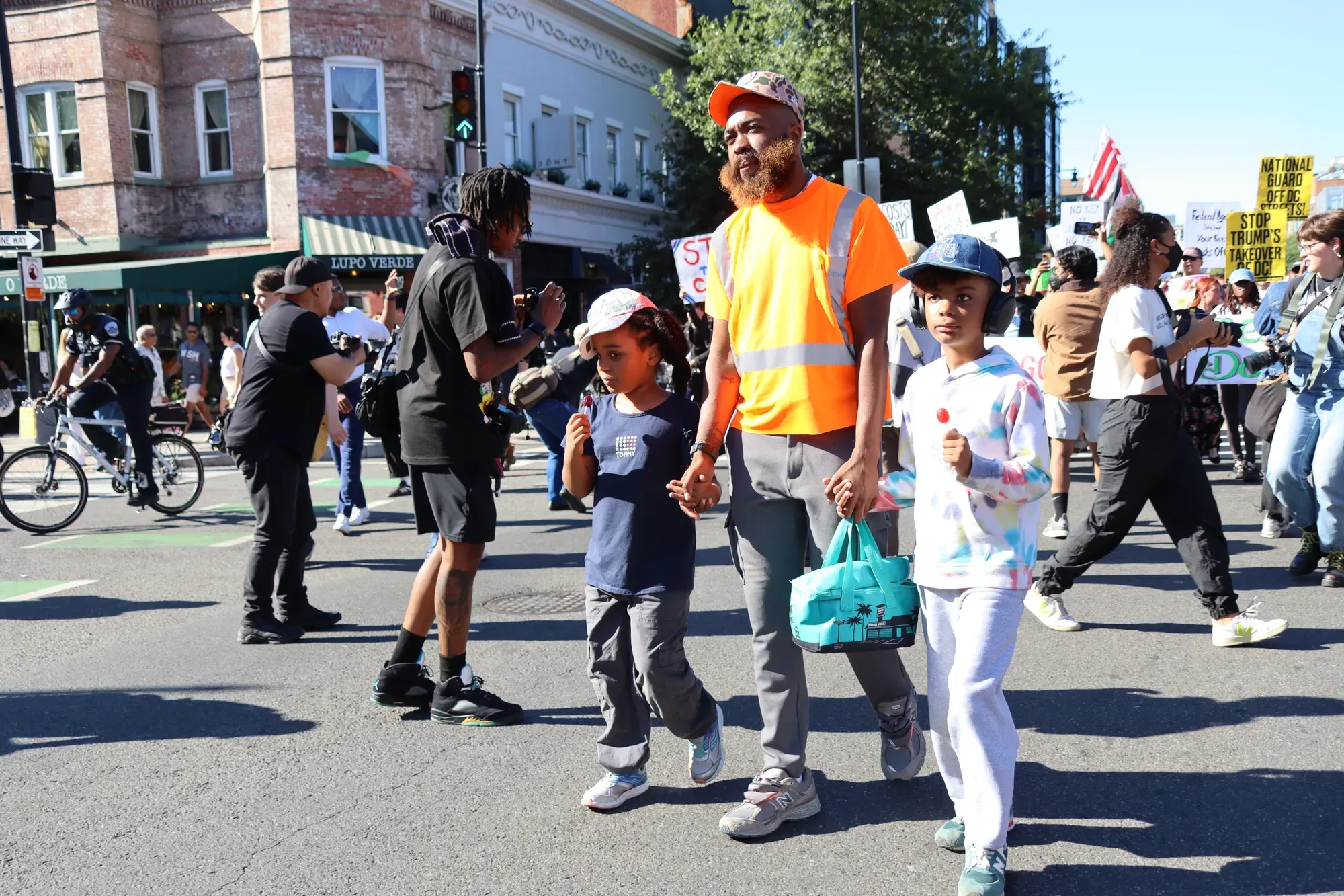 A father holding the hands of his two daughters walks down 14th street in a protest.
