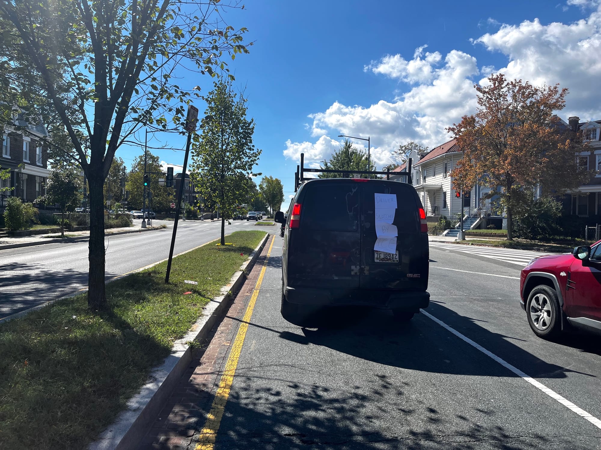 A black van blocks a D.C. road, with four pieces of paper taped to it.