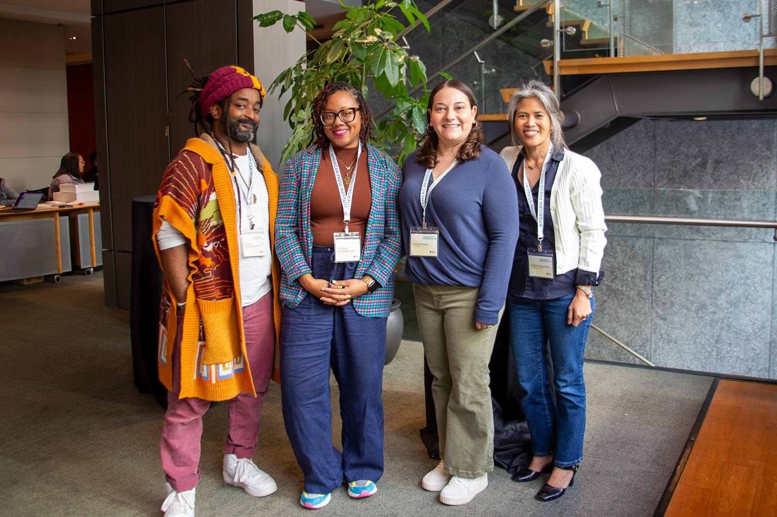 Four people pose for a portrait at a conference, wearing name badges