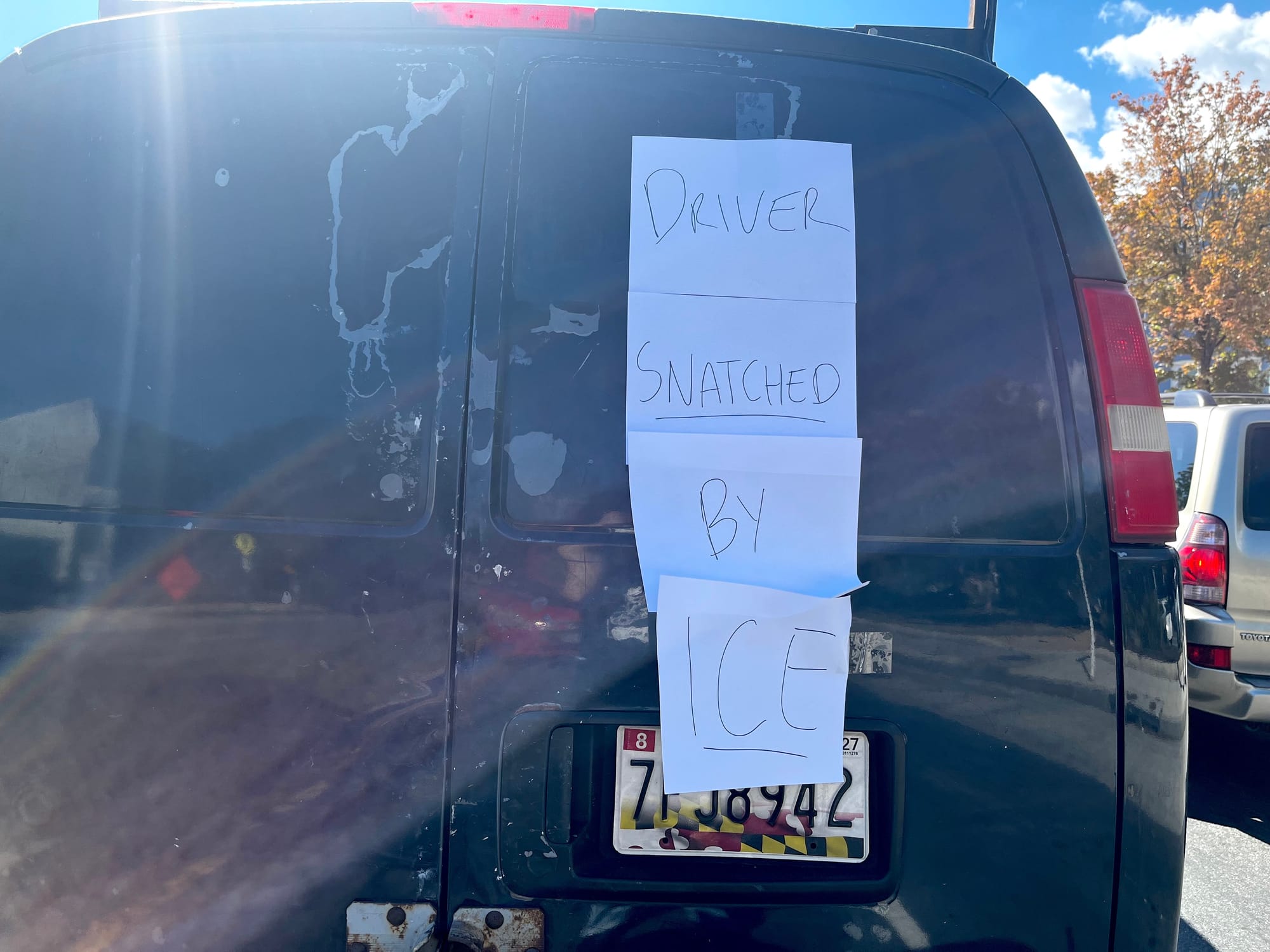 The signs on a black van read "DRIVER SNATCHED BY ICE."
