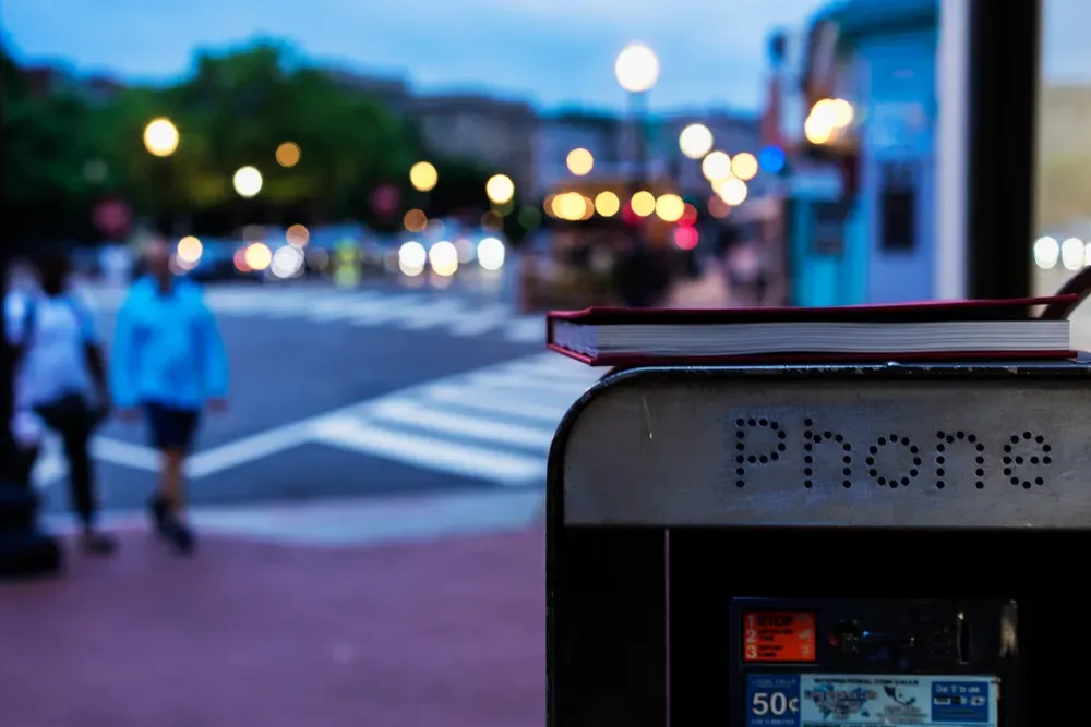 A phone booth with a book resting on top at dusk in Mount Pleasant, D.C.