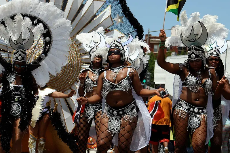Women adorned in festive carnival wear parading in the street.