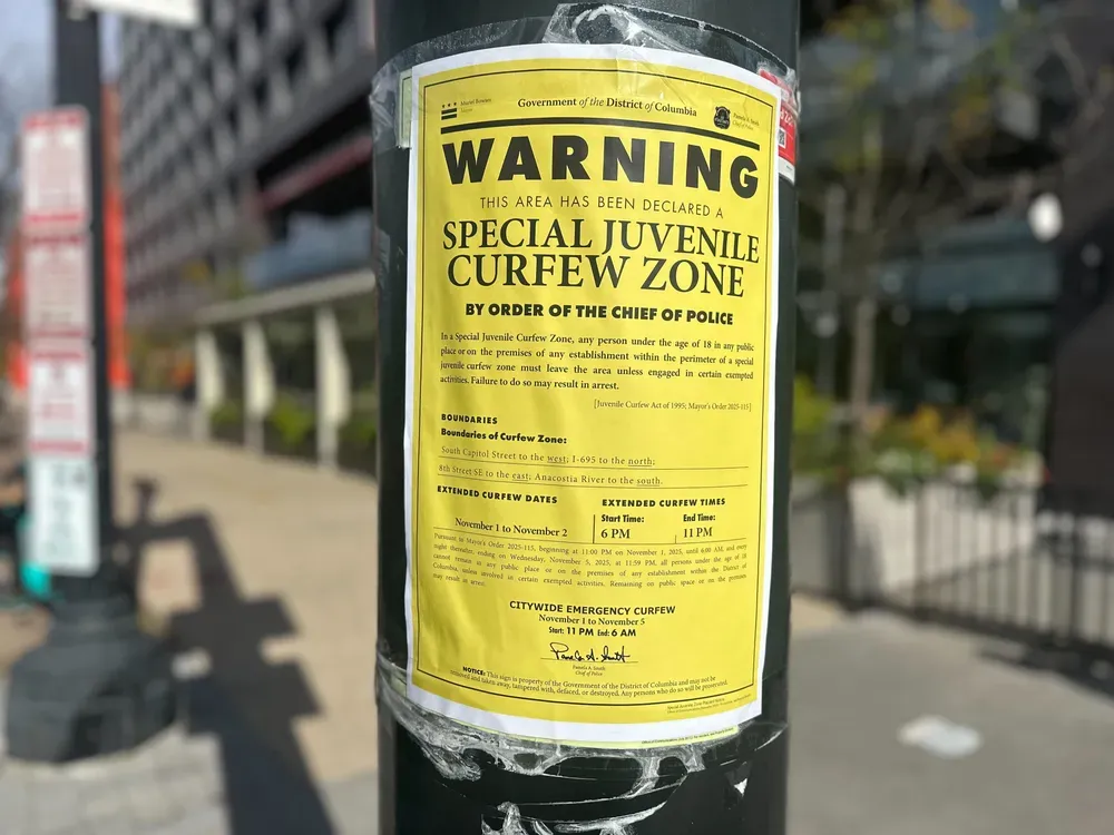 A close up image of a yellow flier stating "Warning this area has been declared a special juvenile curfew zone by the order of the chief of police" posted to a pole.