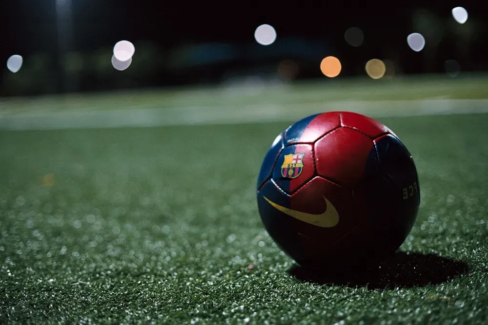 A blue and red soccer ball sitting on a pitch in the dark