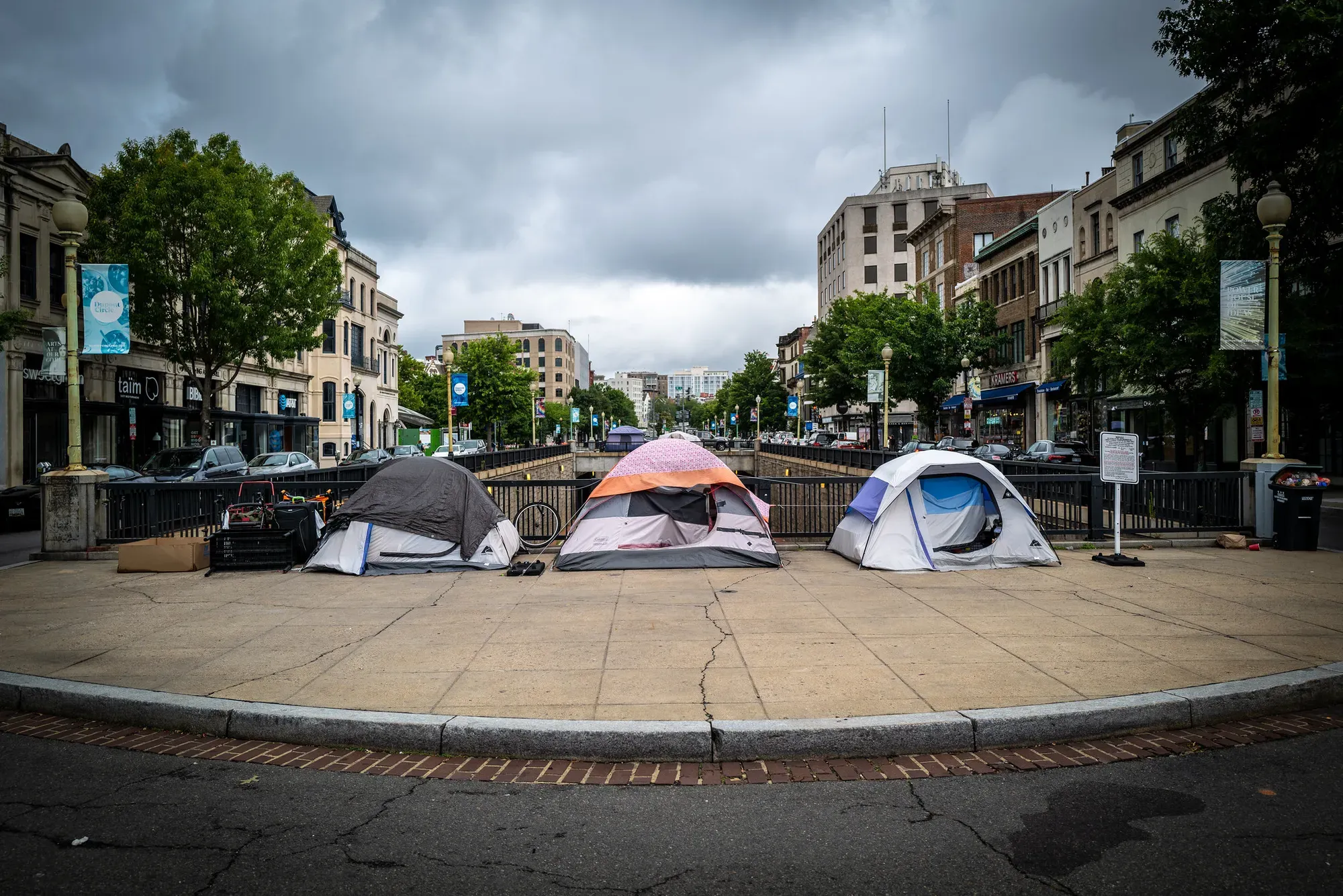 Three tents in D.C.'s Dupont Circle under a cloudy sky.