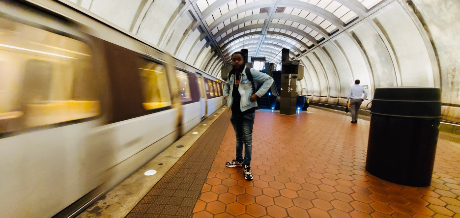 A man stands next to a moving train in a D.C. Metro stop.