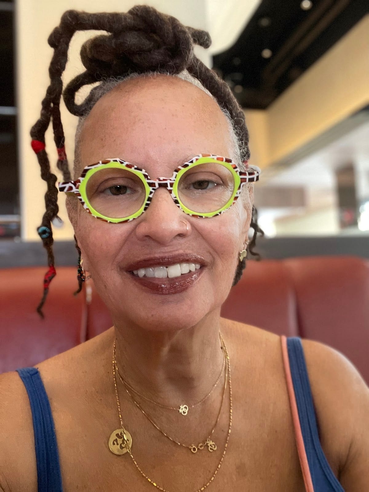 A portrait of a Black woman wearing speckled black, white, and neon glasses.