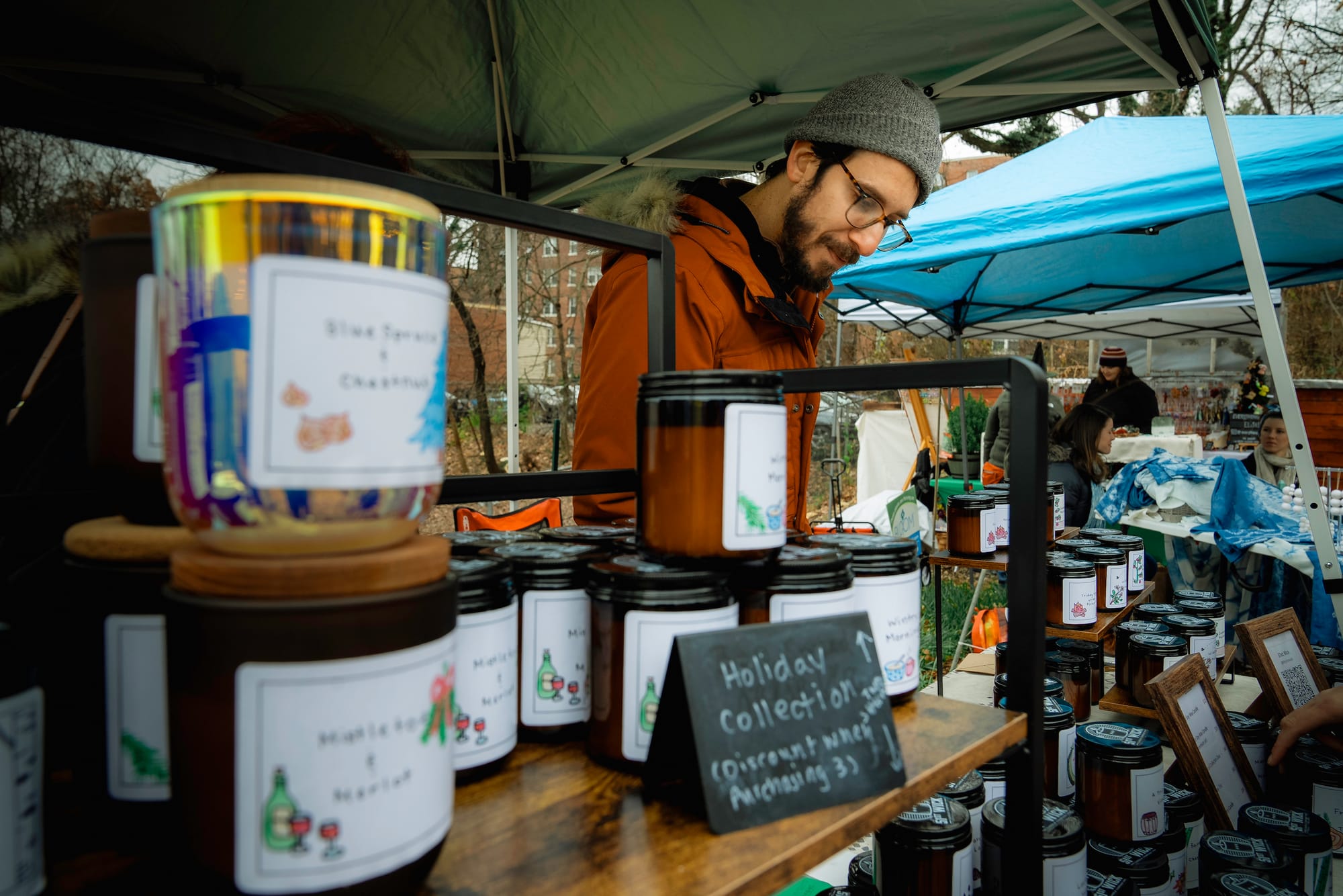 A vendor sells candles at an outdoor holiday market.
