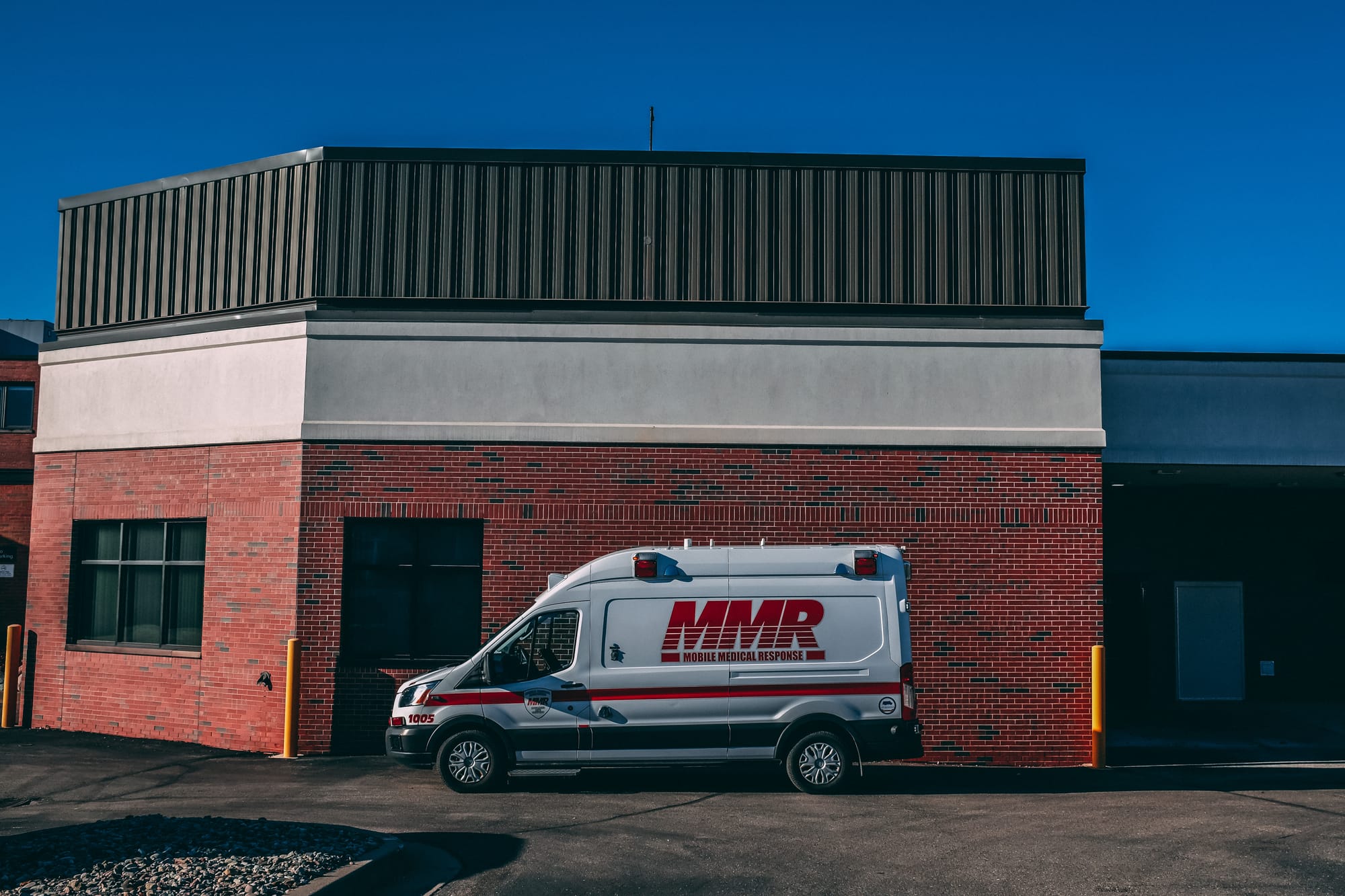 An emergency vehicle parked in an empty lot outside a red brick medical facility.