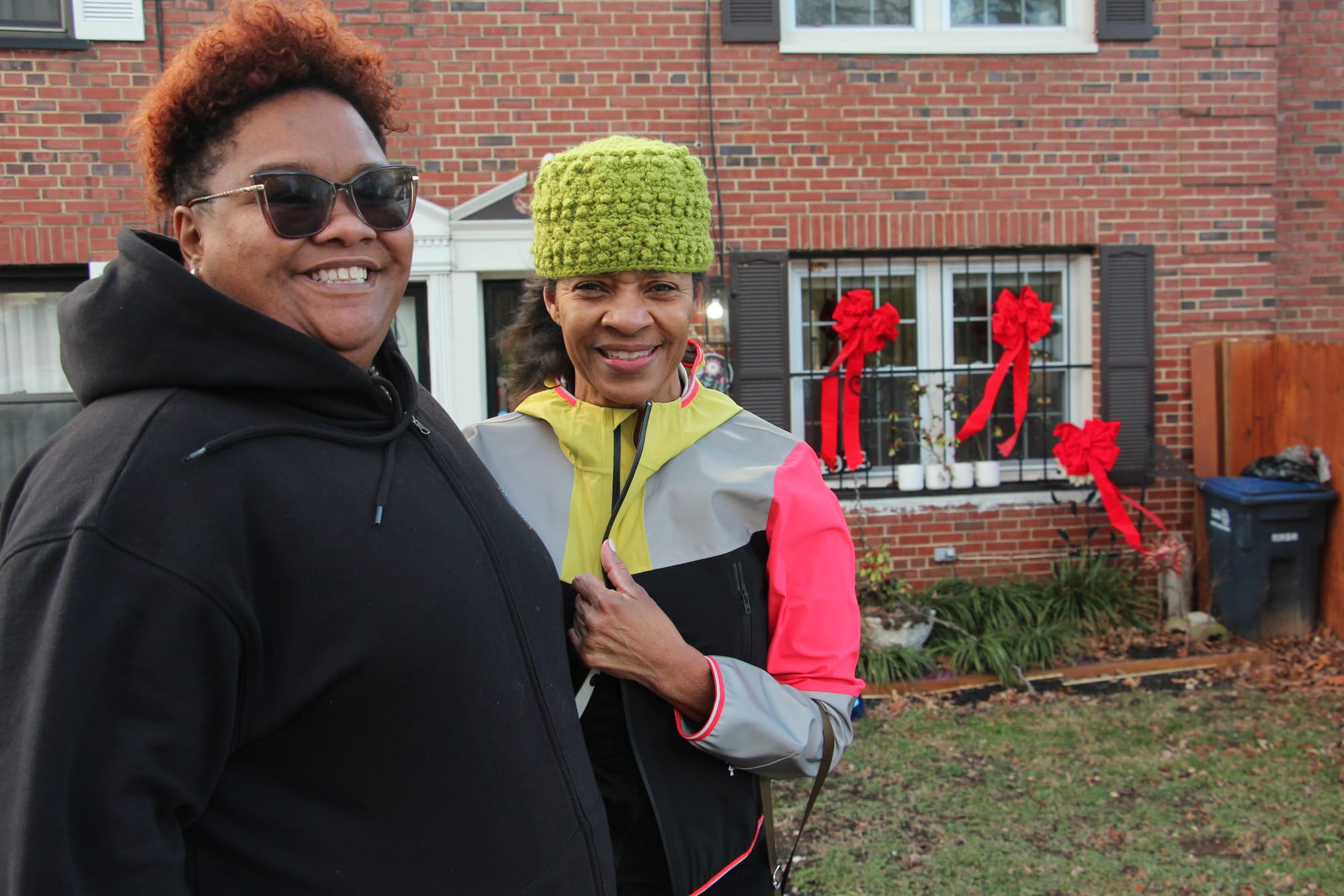 Two people outside of a red brick building smiling.