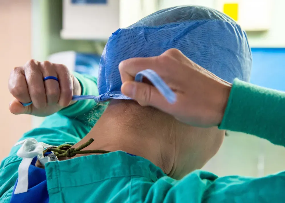 A medical worker ties their green and blue scrubs